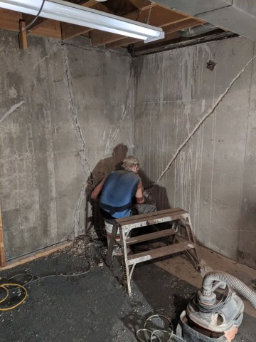 Foundation crack repair in Cold Lake basement with RAMCO technician using chisel before waterproofing